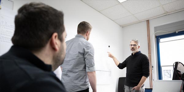 3 men talking around a whiteboard